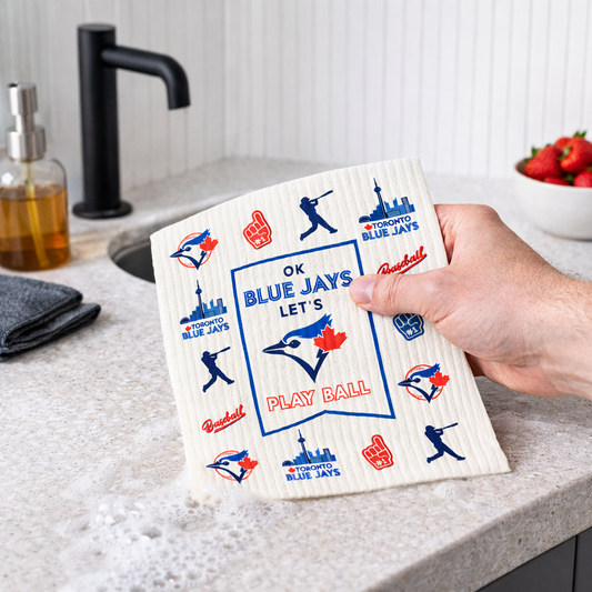 Hand holding a kitchen Swedish dishcloth with Blue Jays logo on a kitchen counter