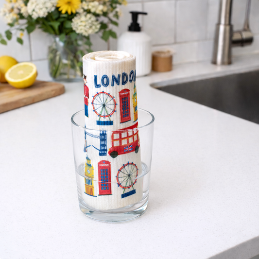 Rolled london inspired swedish cloth in a glass on a kitchen counter with lemons and flowers in the background.